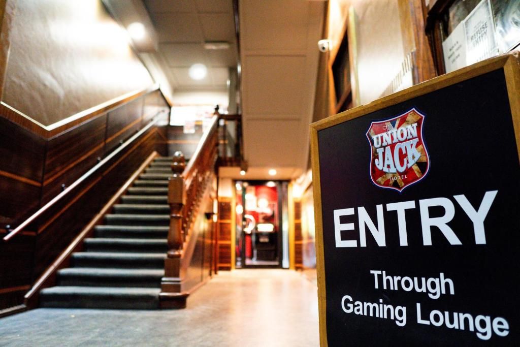 A sign indicating entry through the gaming lounge of the Union Jack Hotel.