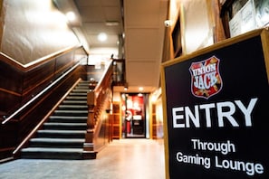 A sign indicating entry through the gaming lounge of the Union Jack Hotel. - The Jack Backpackers (Cairns)