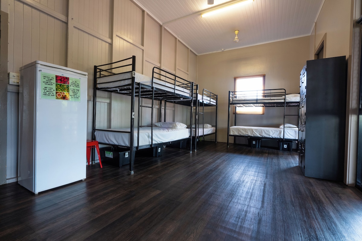 Un dormitorio con literas, un refrigerador y una ventana con persianas.