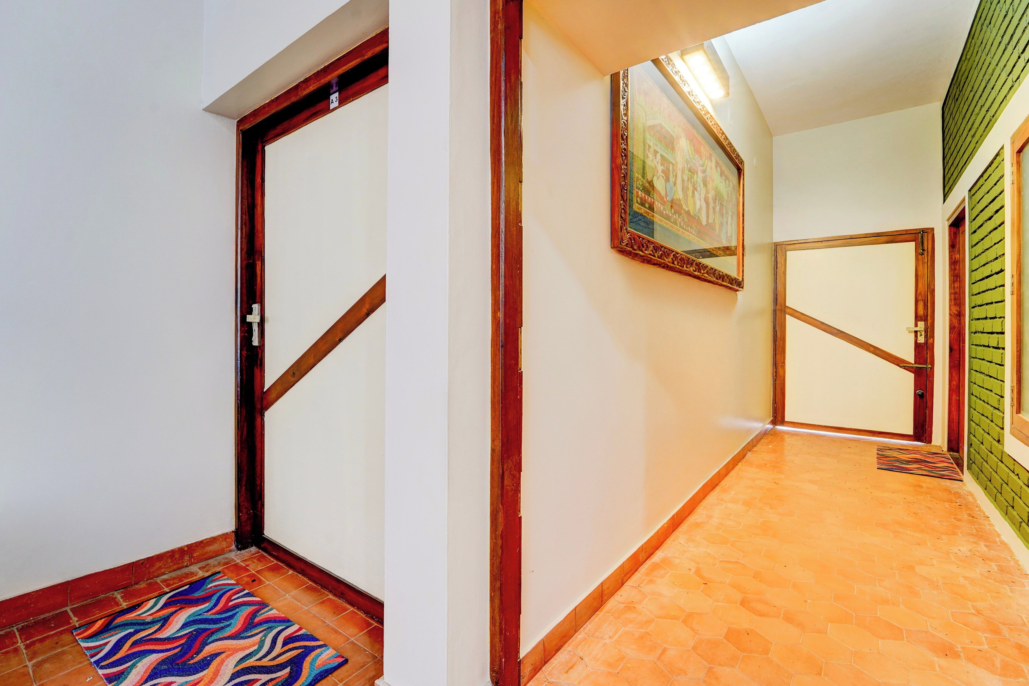 A hallway with a tiled floor, a wooden door, and a wall-mounted picture.