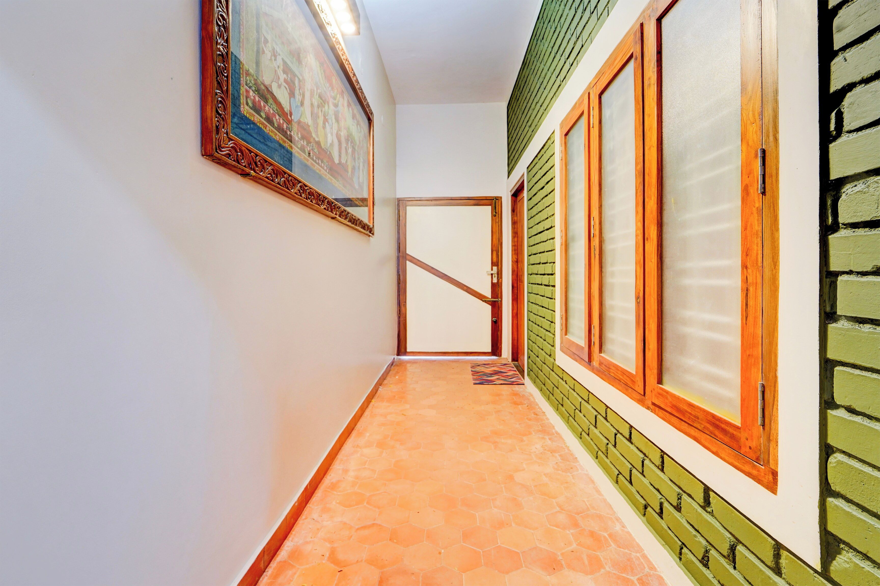 A hallway with a tiled floor, a door at the end, and a window with a wooden frame.