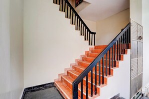 Una escalera con barandilla negra y peldaños anaranjados que conducen a una plataforma.