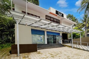 A hotel with a covered entrance, a staircase leading to the entrance, and a view of the surrounding greenery. - Hotel O CSIR Pappanamcode (Thiruvananthapuram)
