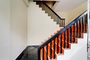 A staircase with black handrails and red steps, leading to an upper floor. - Hotel O CSIR Pappanamcode (Thiruvananthapuram)