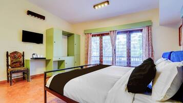 A hotel room with a bed, a chair, a desk, a television, and a window with curtains.