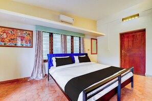 A hotel room with a bed, curtains, a painting, and a wooden door. - Hotel O CSIR Pappanamcode (Thiruvananthapuram)