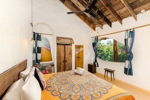 Ein Schlafzimmer mit einem großen Bett, einer Holzbalkendecke, einem Fenster mit Vorhängen und einer Holztür.