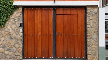 Een dubbele houten garagepoort met een stenen muur en het getal '7079' erboven.