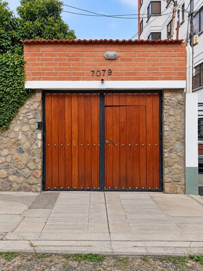 Une porte de garage double en bois, avec un mur en pierre et le numéro « 7079 » au-dessus.