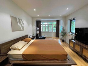 A hotel room with a large bed, a desk, a chair, a television, and a window with curtains. - OH Trendy homes Hoan Kiem LTK - Balcony City VIew (Cua Nam)