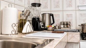 A kitchen with a stainless steel sink, a blender, a coffee maker, and a cutting board.