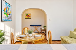 Un coin repas avec une table ronde, des chaises et un banc bleu rembourré.