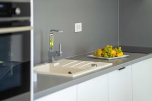 A modern kitchen with a white sink, a stainless steel faucet, and a fruit bowl on the countertop. - Villa Sanja (100711-K1) - Vizinada (Porec) (Vizinada (Porec))