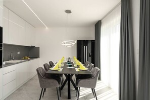 Un espace repas moderne avec une table noire, des chaises grises et un luminaire original.