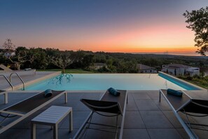 Une piscine avec des chaises longues et une vue sur le coucher de soleil.