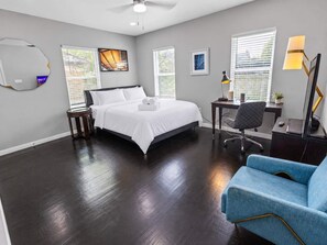 Une chambre d’hôtel avec un lit, un bureau, une chaise et un fauteuil bleu.
