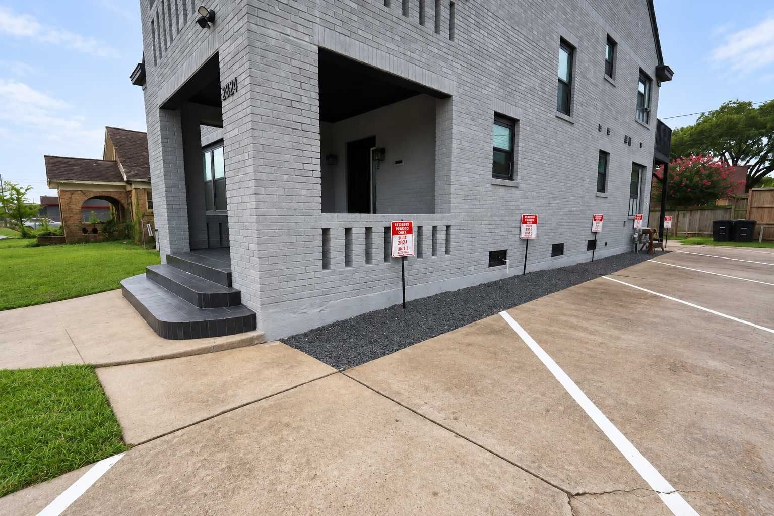 Un bâtiment moderne avec une façade en briques, un parking et un espace vert.