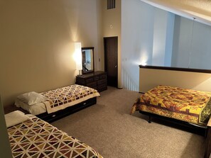 Un dormitorio con dos camas, un aparador, un espejo y una ventana con cortinas.