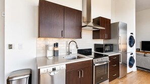 A modern kitchen with stainless steel appliances, a dishwasher, and a built-in oven. - Roami at Studio 135 - Modern and Spacious 2BR (Denver)