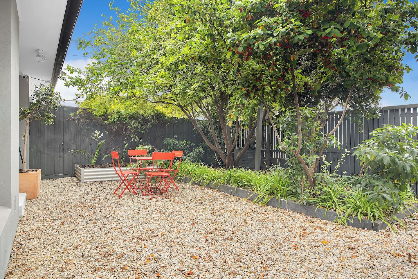 A patio area with a table and chairs, surrounded by gravel and plants.