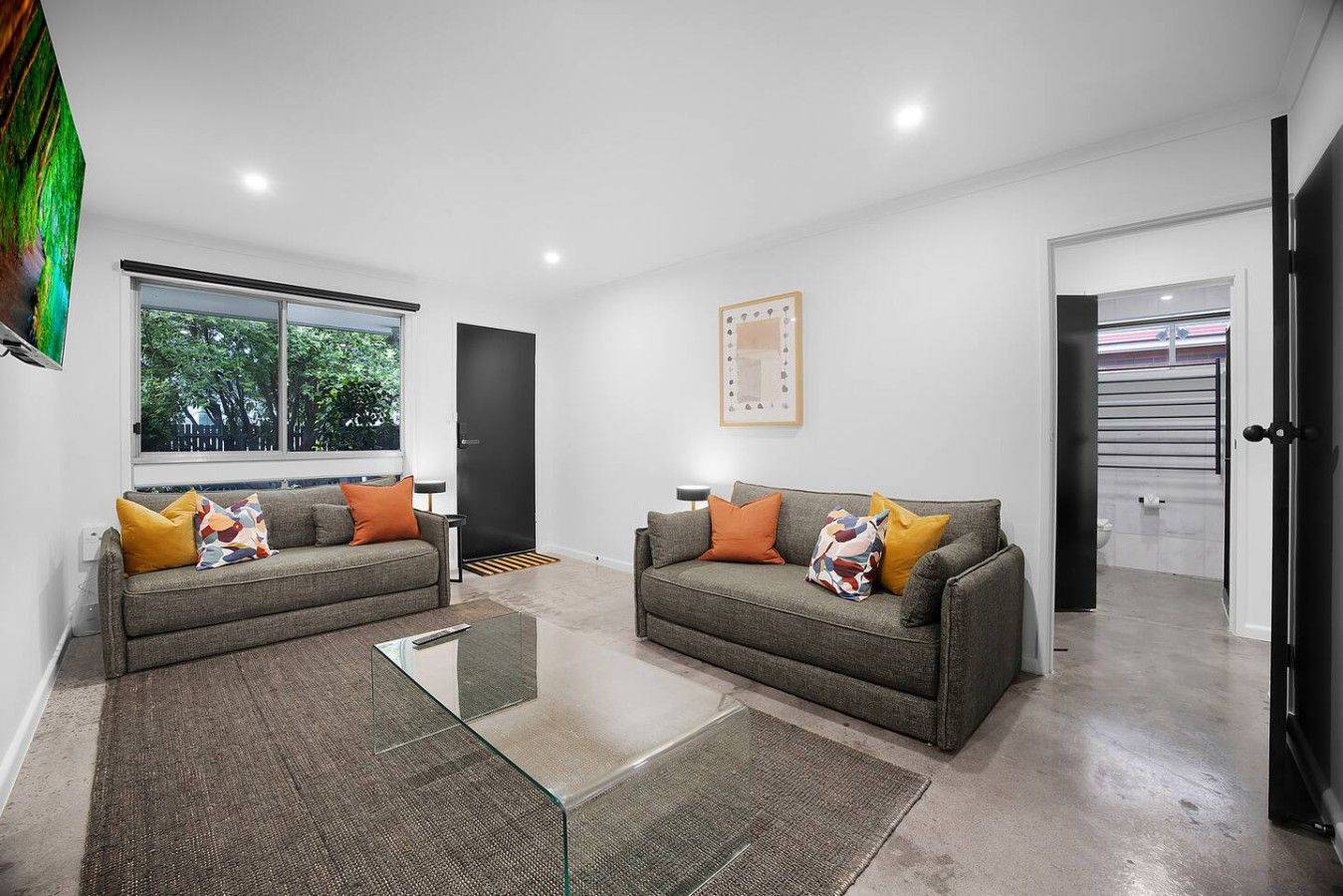 A modern living room with two sofas, a glass coffee table, and a large window.