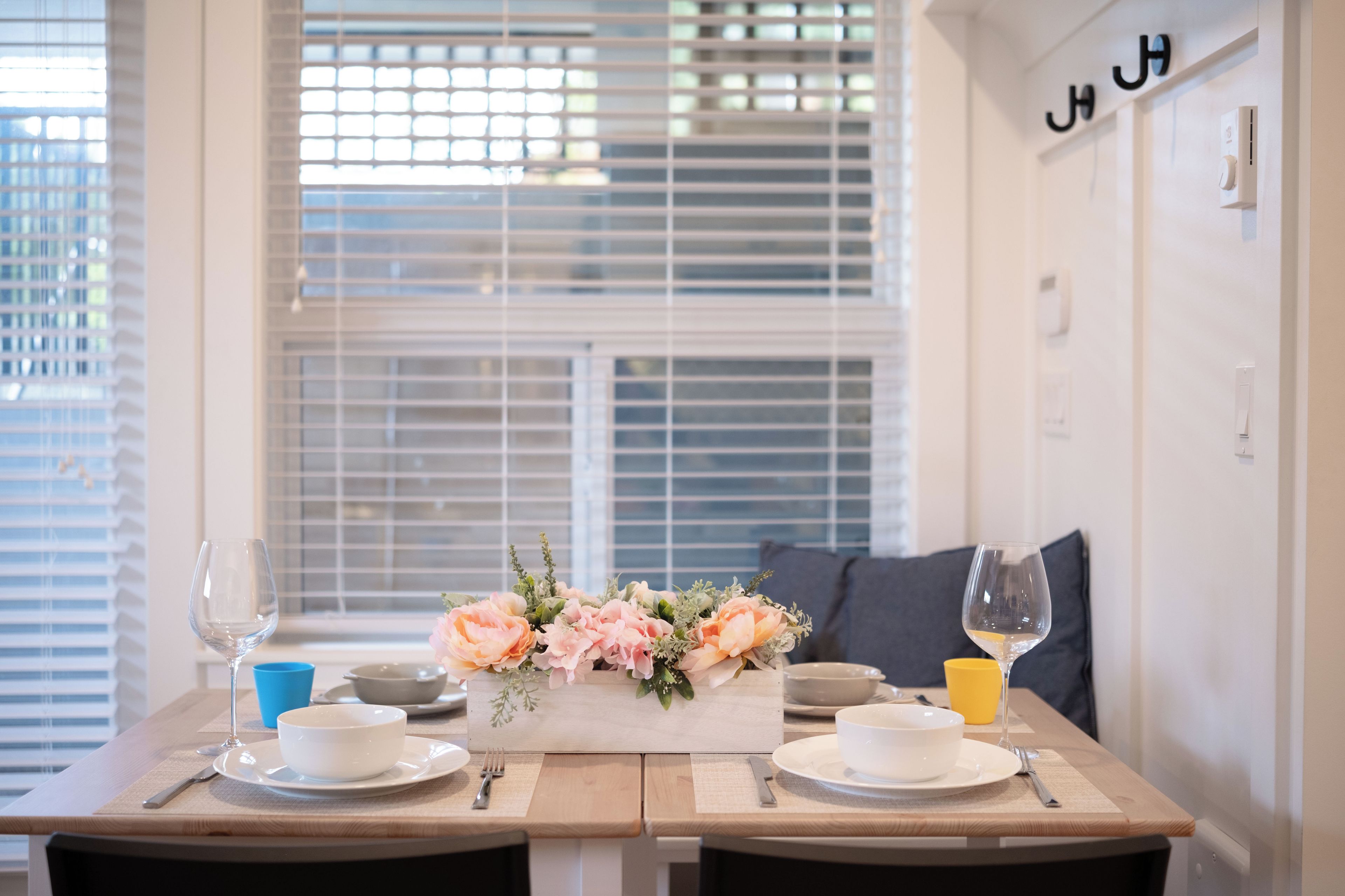 A dining table set with white plates, bowls, cutlery, and glasses, with a floral centerpiece.