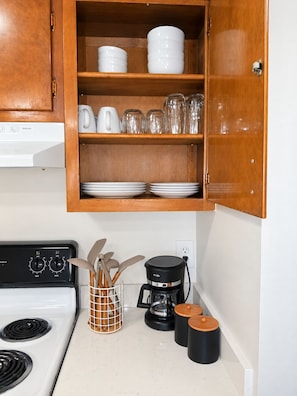 A kitchen with a stove, coffee maker, and utensils on the counter. - Mid-Century Modern #12 + 2nd floor + 1 Bed/1 Bath (Lansing)