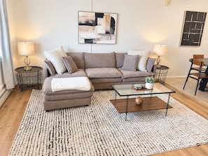 A living room with a sofa, coffee table, and two lamps. - Mid-Century Modern #12 + 2nd floor + 1 Bed/1 Bath (Lansing)