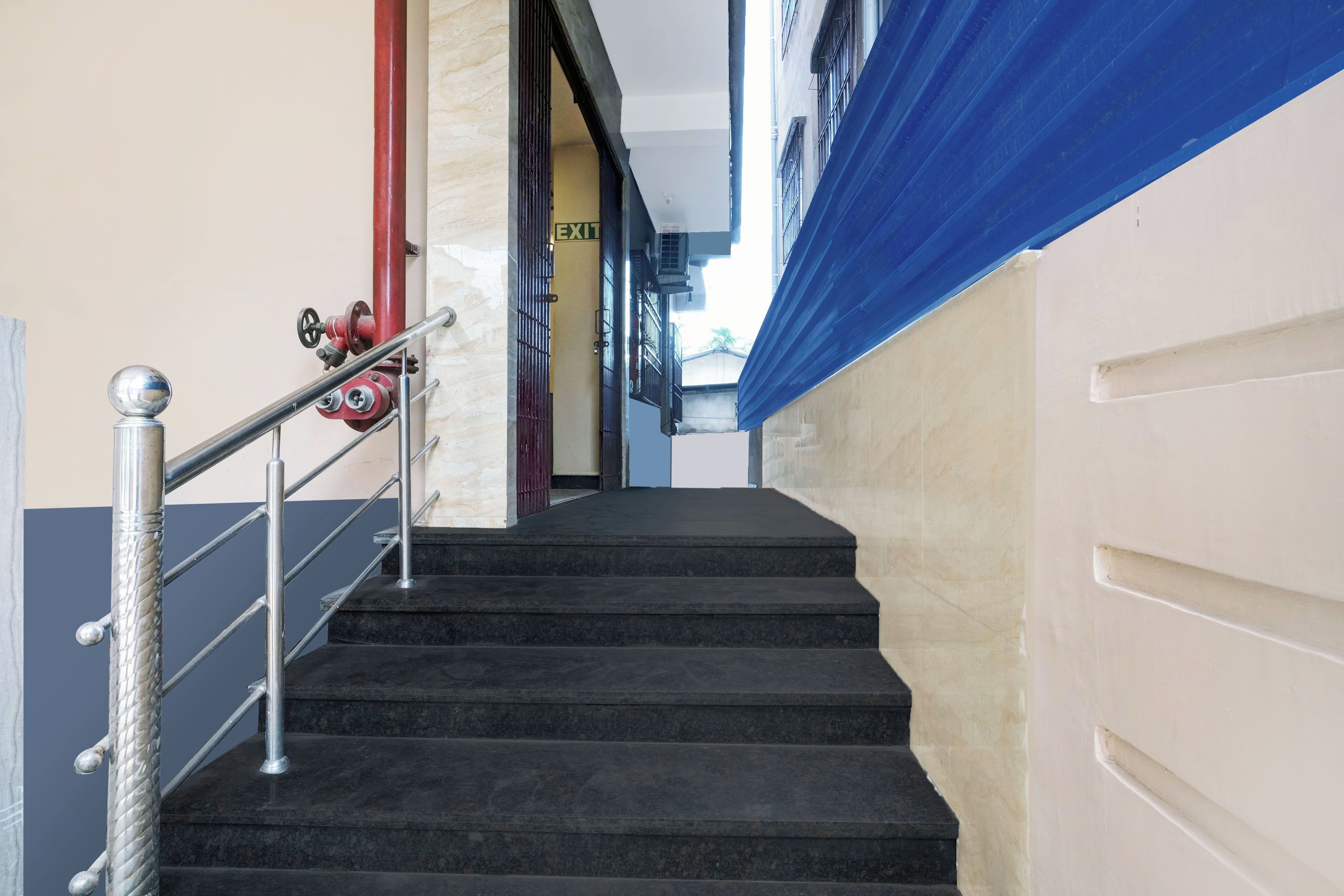 Una escala amb barana metàl·lica que condueix a una porta de sortida.