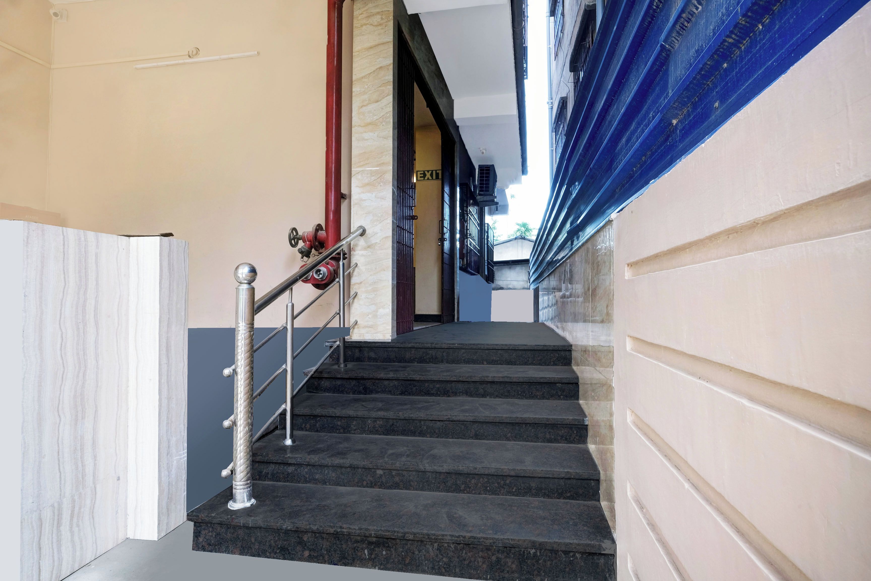 Una escalera con barandilla de metal que lleva a una puerta señalizada con 'EXIT'.