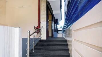 Un escalier avec une rampe métallique menant à une porte marquée « SORTIE ».