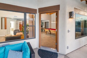 A modern living room with a pool table, a sofa, and large windows. - Desert Hilltop Oasis in Foothills Epic (Tucson)