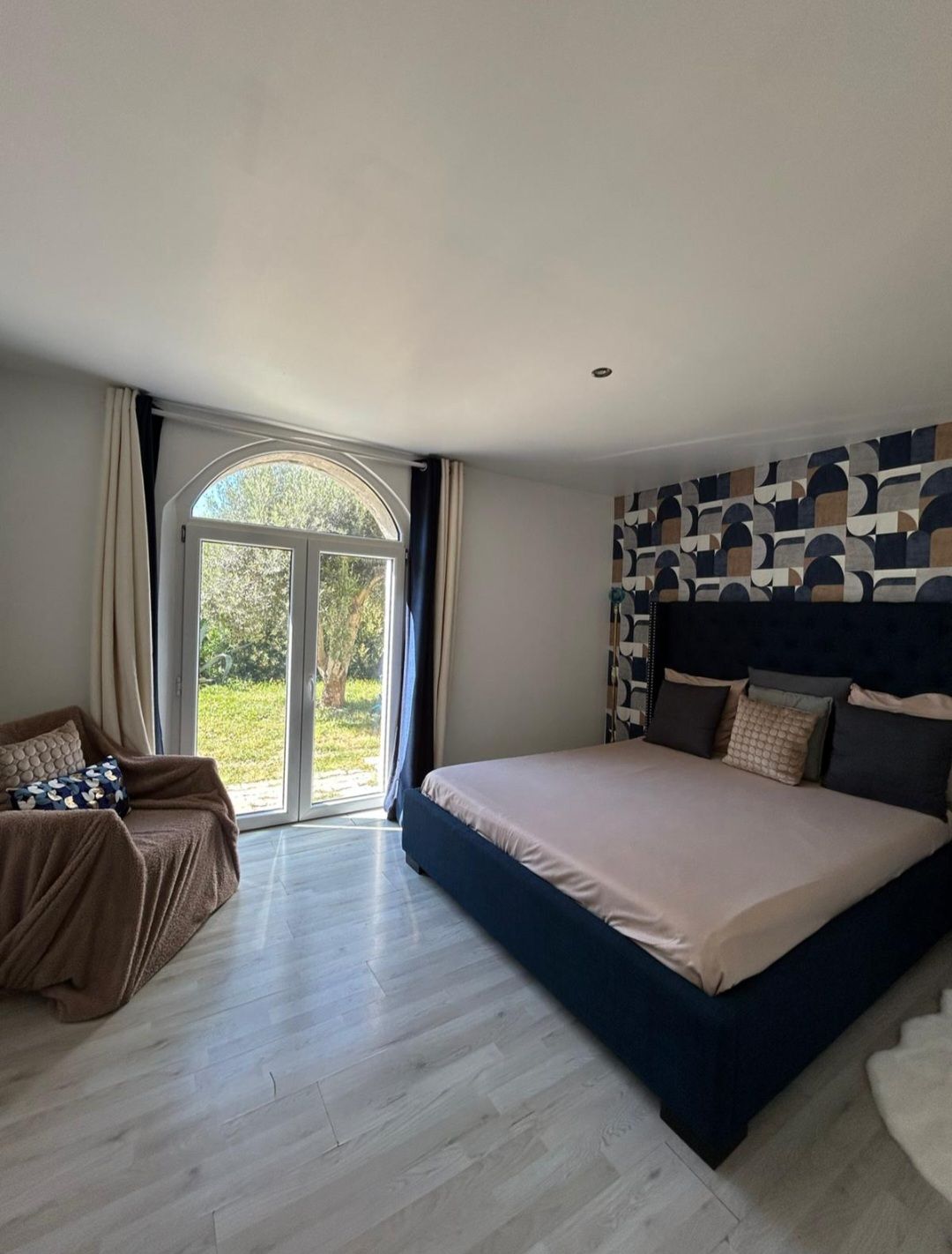 Een slaapkamer met een groot bed, een slaapbank en een schuifdeur naar buiten.