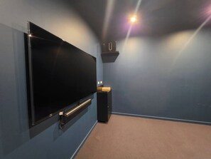 A room with a large flat-screen TV mounted on the wall, a speaker, and a small shelf. - Kingston 1BR in a Central Foreshore Location (Canberra (Inner South))