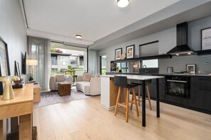 A modern kitchen with a central island, bar stools, and a built-in oven. - Kingston 1BR in a Central Foreshore Location (Canberra (Inner South))