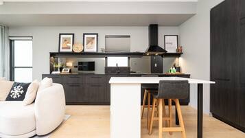 A modern kitchen with a central island, dark cabinetry, and a dining area with a white table and bar stools.
