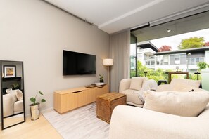 A modern living room with a flat-screen TV, a sofa, a coffee table, and a side table. - Kingston 1BR in a Central Foreshore Location (Canberra (Inner South))