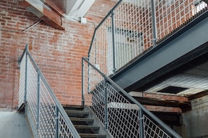 A metal staircase with a brick wall background. - Wall Street Suites 3 | Queen Studio near SIU with Kitchen (Carbondale)