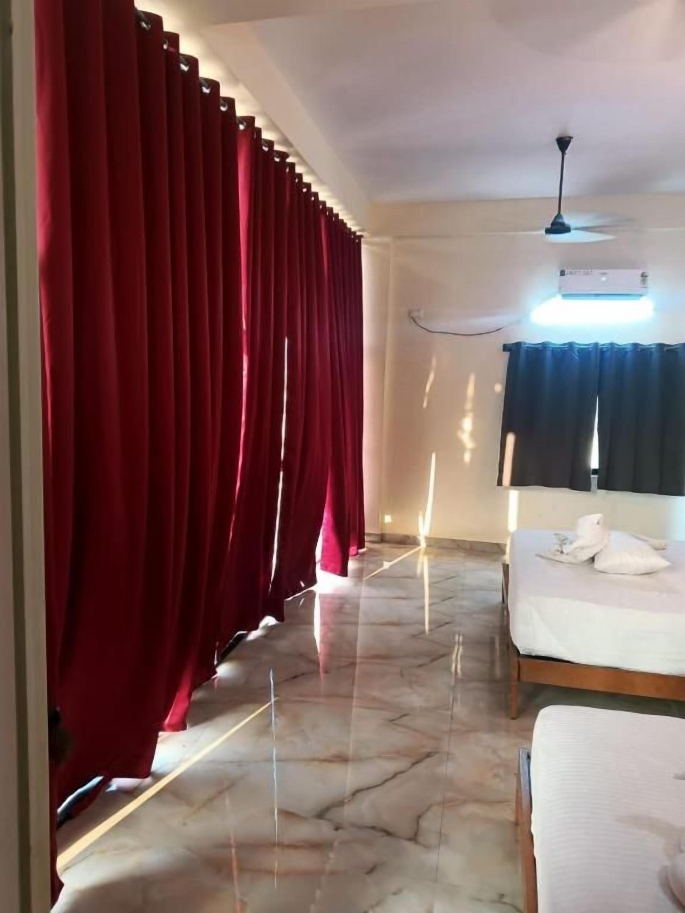 A hotel room with a bed, a ceiling fan, and a window with curtains.
