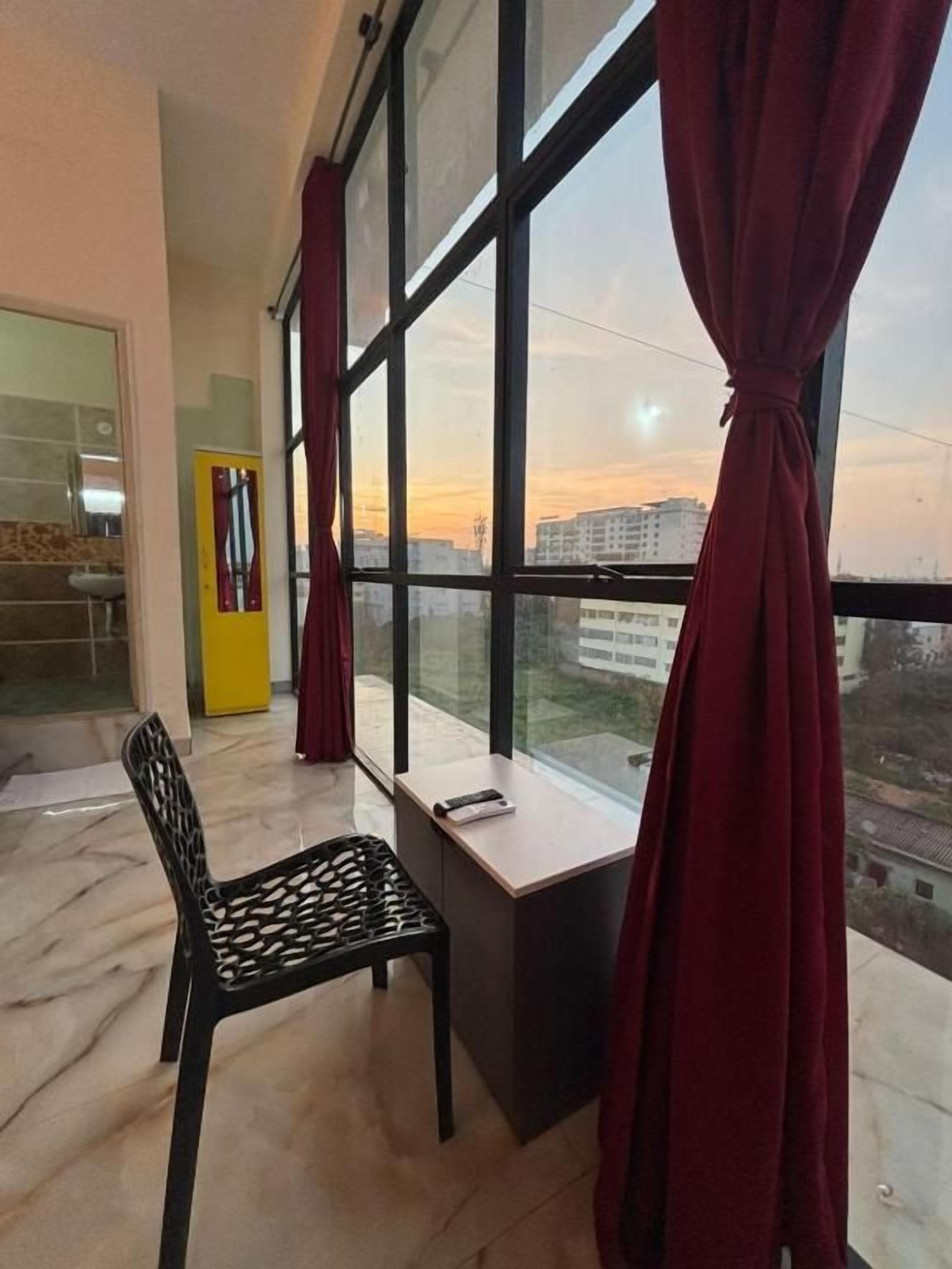 Ein Balkon mit Stuhl, Tisch und Blick auf Gebäude sowie einen Sonnenuntergang.