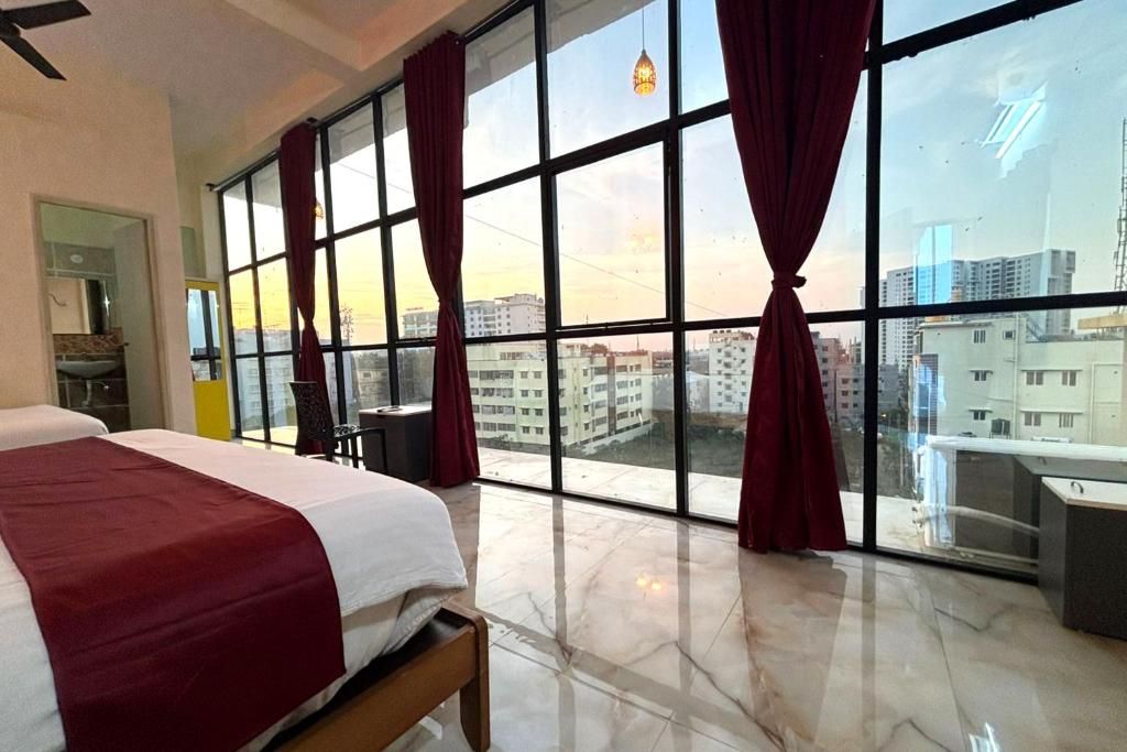 Ein Hotelzimmer mit großem Fenster, einem Bett, einem Schreibtisch und einem Sessel.
