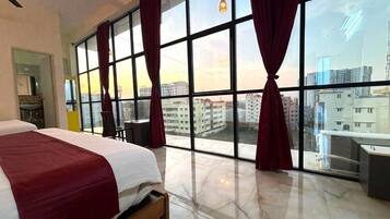 Ein Hotelzimmer mit großem Fenster, einem Bett, einem Schreibtisch und einem Sessel.
