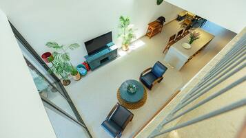 Een ruime woonkamer met een flatscreen-tv, zitgedeelte en potplanten.