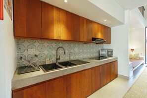 A modern kitchen with wooden cabinets, a stainless steel sink, and a patterned backsplash. - Sunrise Villa 4BR Tan Thanh Beachside by Beachside Boutique Homes (Đà Nẵng)