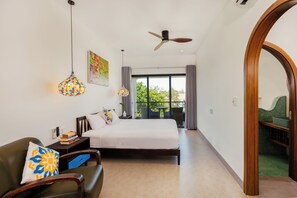 A hotel room with a bed, a desk, a chair, a ceiling fan, and a view of the outdoors. - Sunrise Villa 4BR Tan Thanh Beachside by Beachside Boutique Homes (Đà Nẵng)