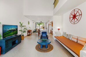 Sala de estar moderna com televisão, área de estar e um objeto decorativo na parede.