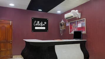 En receptionsdisk med en skylt som visar att den är bemannad av företagets personal, en väggmonterad luftkonditioneringsanläggning och en anslagstavla med diverse meddelanden.