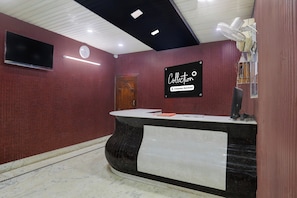 A reception area with a marble counter, a clock, and a sign indicating it's a company-serviced collection point.