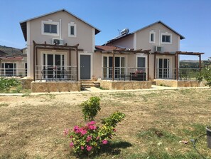 A two-story house with a stone foundation, large windows, and a covered patio area. - Daphne's Apartment (Kefalonia)
