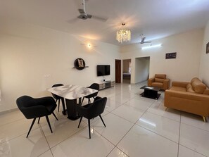 Ein modernes Wohnzimmer mit Essbereich, einer Couch, einem Fernseher und einem Kronleuchter.